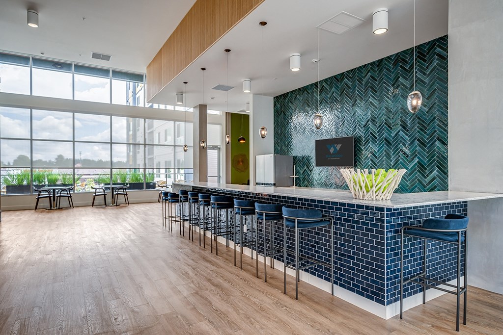 a long bar with blue chairs and a large window