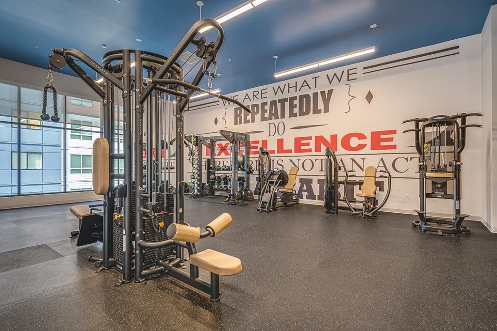 a workout room with weights and cardio equipment and a wall with are what we