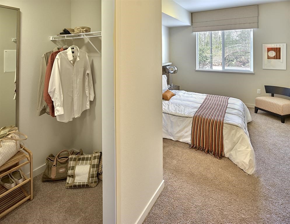 A bedroom with a bed, a closet, and a window.