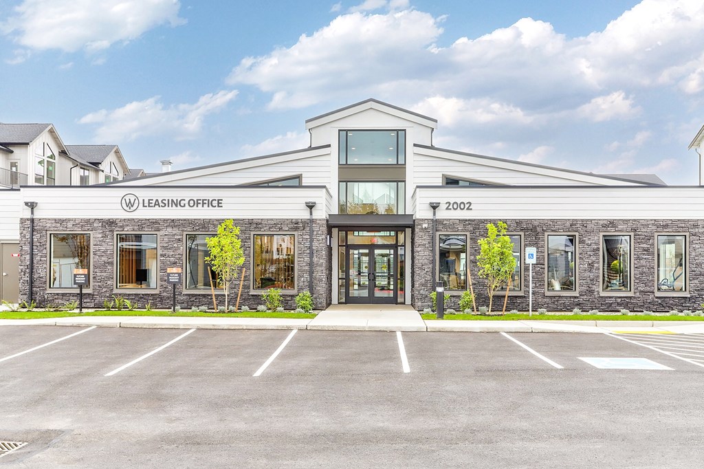 A leasing office building with a parking lot in front.