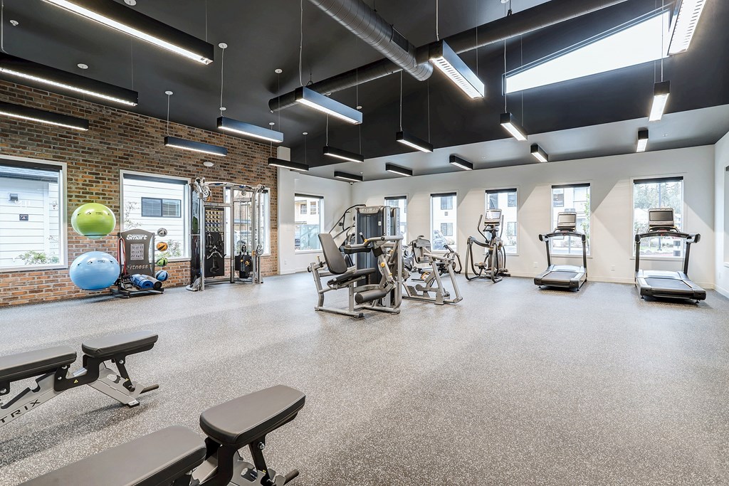 a gym with cardio equipment and weights in a building with brick walls