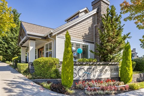 A house with a sign that says "Sunset Cedar Mill Apartment Homes".