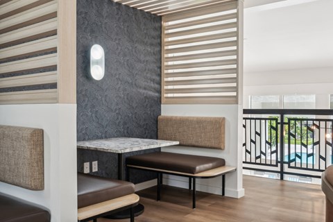 a seating area with benches and a table in a room with a balcony