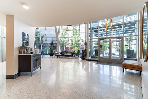 A spacious lobby with a bench, a reception desk, and a view of the outdoors through large windows.