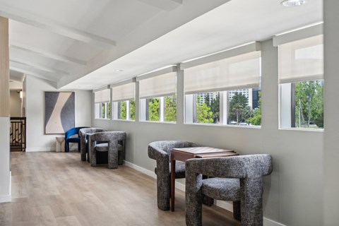 a living room with a row of windows and a table with chairs