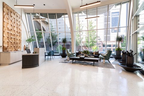 A modern waiting room with a wooden panel on the wall and a view of the city outside the windows.