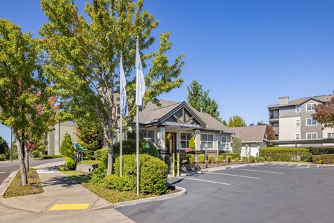 A parking lot with a building in the background and trees in the foreground.