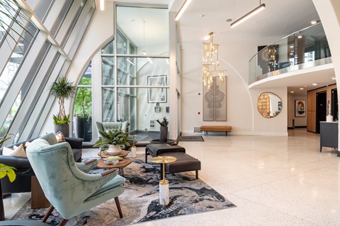 A modern living room with a glass wall and a large window.