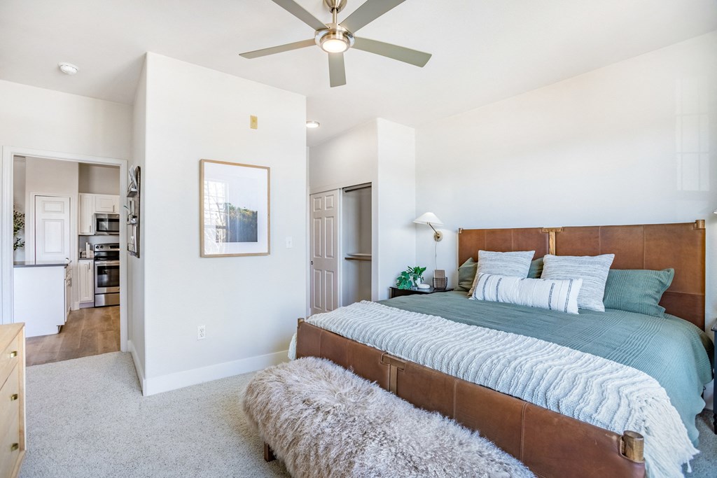 A bedroom with a large bed and a ceiling fan. at The Viridian Apartments, Colorado