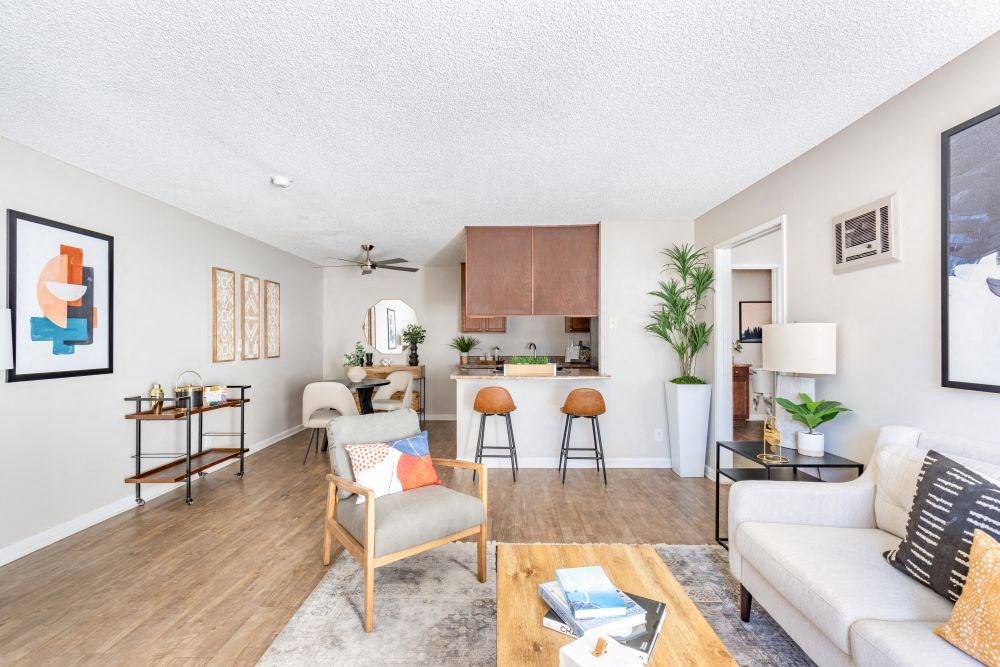 A living room with a white couch, a wooden coffee table, and a kitchen area in the background.