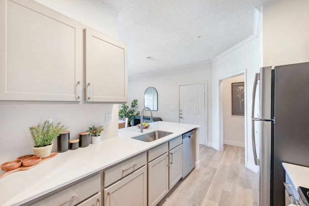A kitchen with white countertops and a stainless steel refrigerator.