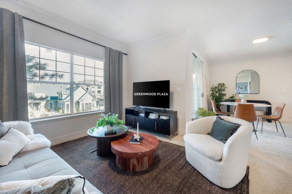 A living room with a white couch, a wooden coffee table, and a flat screen TV.