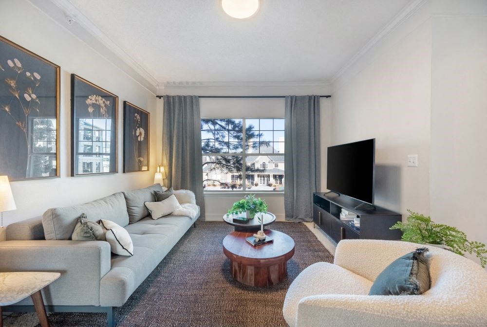A living room with a grey couch, a coffee table, and a flat screen TV.