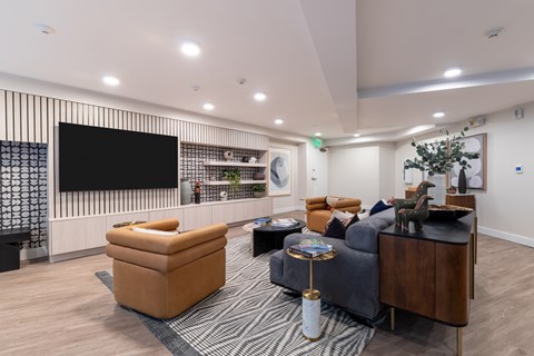 A living room with a grey couch, a yellow chair, and a black and white striped rug.