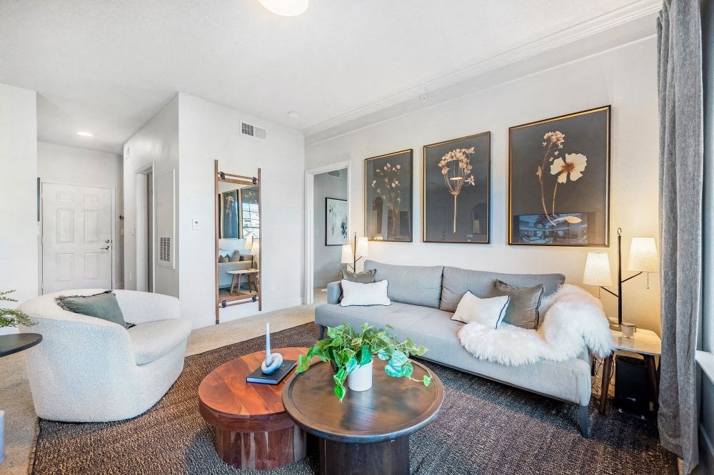 A living room with a grey couch, a coffee table, and a large mirror.