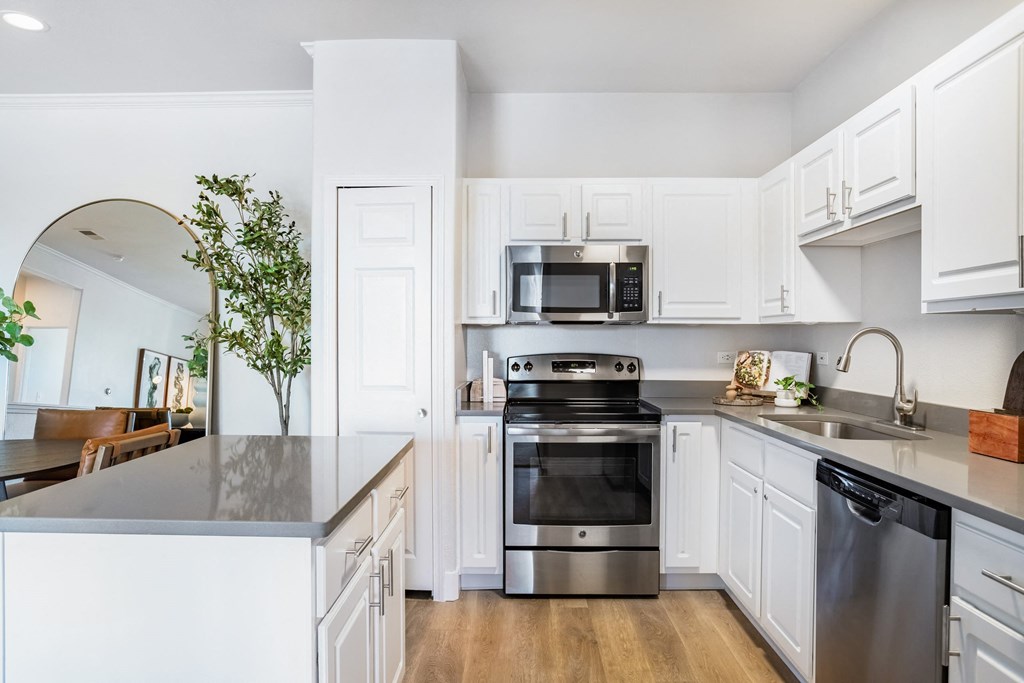 A modern kitchen with a stainless steel oven and white cabinets. at The Viridian Apartments, Greenwood Village, Colorado
