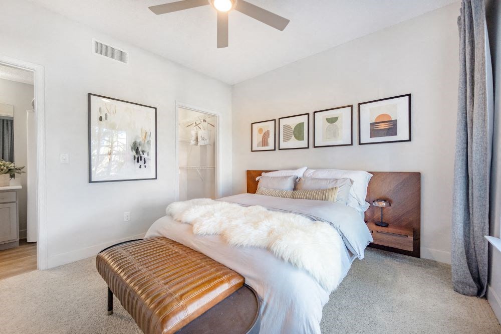 A bedroom with a bed, a bench, and pictures on the wall.