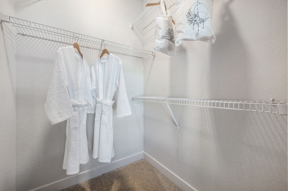 Two white robes hanging on a rack in a room.
