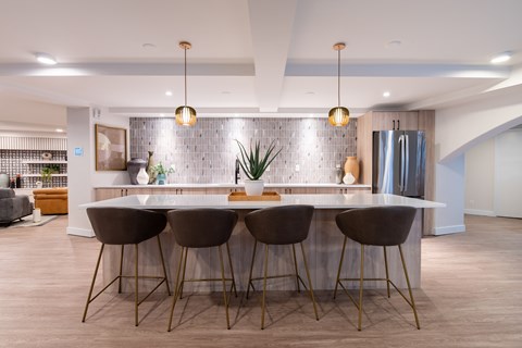 A modern kitchen with a bar area featuring a white countertop and brown chairs.