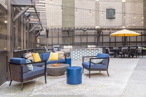 A patio with blue chairs and a yellow umbrella.