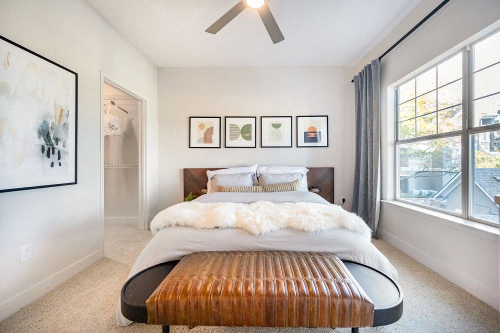 A bedroom with a bed, a bench, and pictures on the wall.