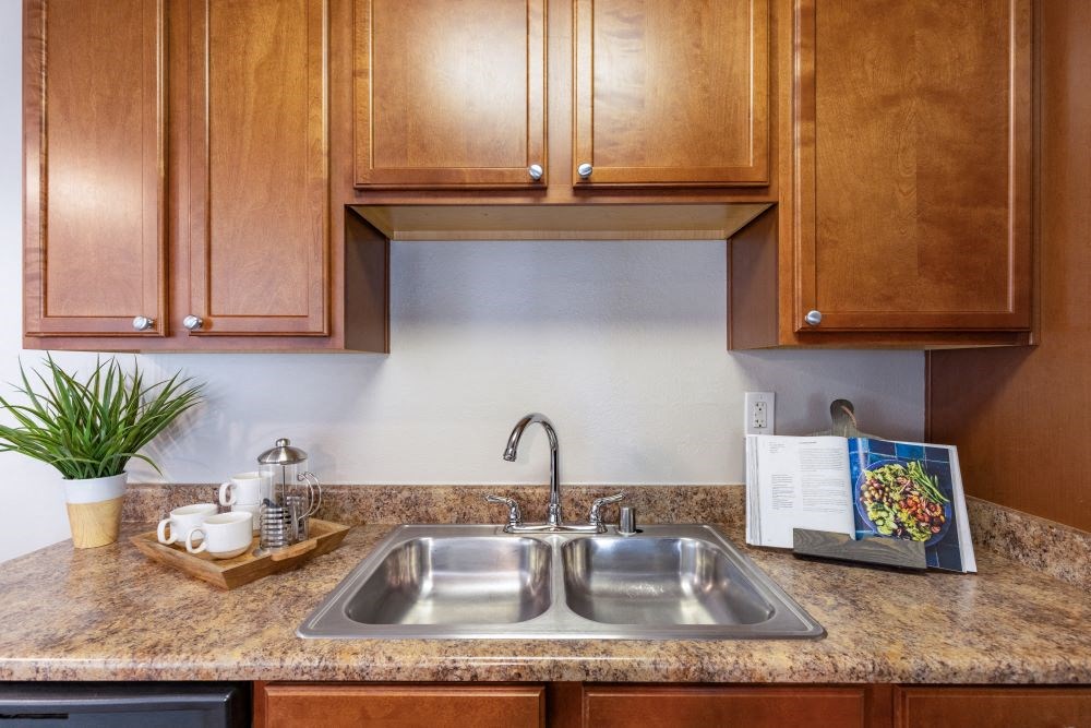 A kitchen with a sink and wooden cabinets.