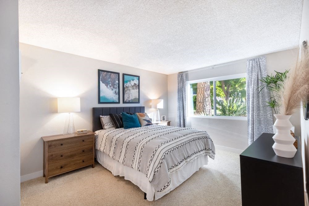 A bedroom with a bed, nightstand, and two pictures on the wall.
