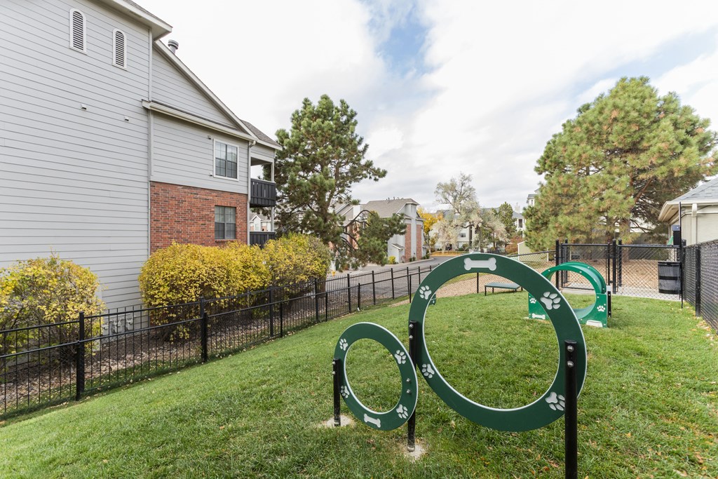 A playground with green rings in the foreground and a residential building in the background.