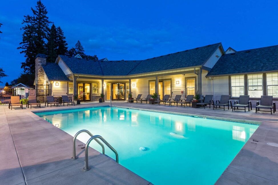 a swimming pool at night in front of a hotel