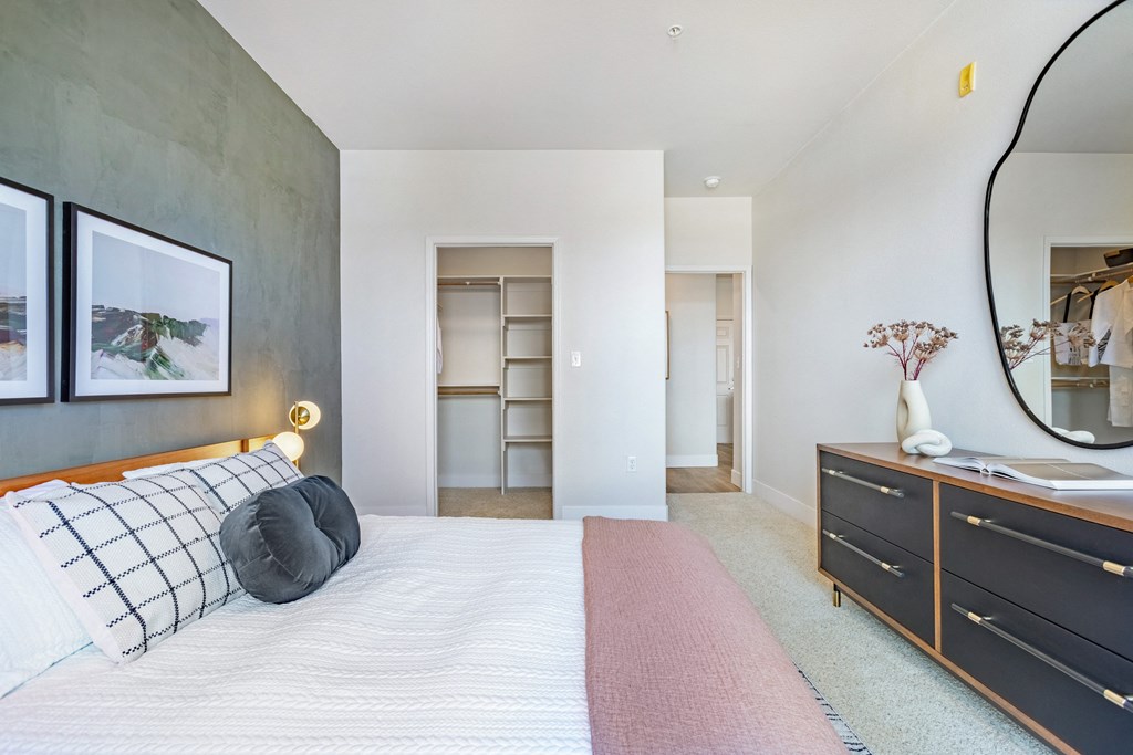 A bedroom with a large bed and a mirror on the wall. at The Viridian Apartments, Colorado, 80111