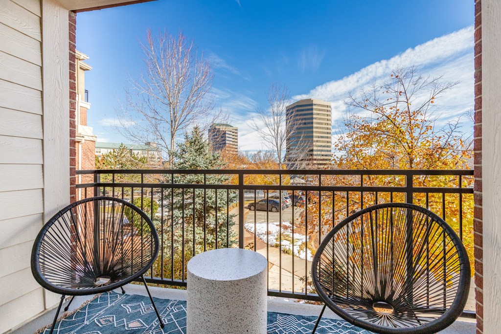 Two black chairs are placed on a balcony with a view of the city. at The Viridian Apartments, Greenwood Village 80111