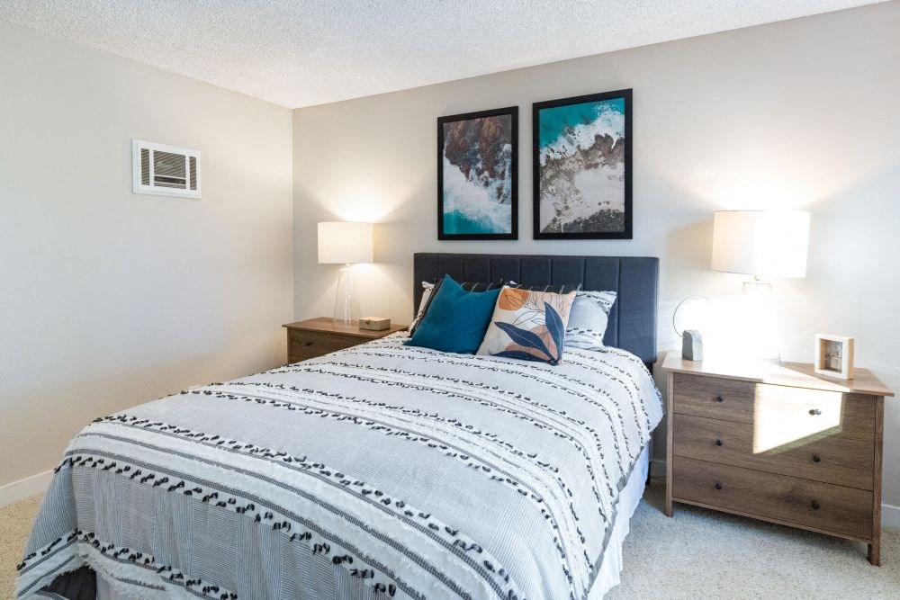 A bedroom with a bed, nightstand, and two wall lamps.