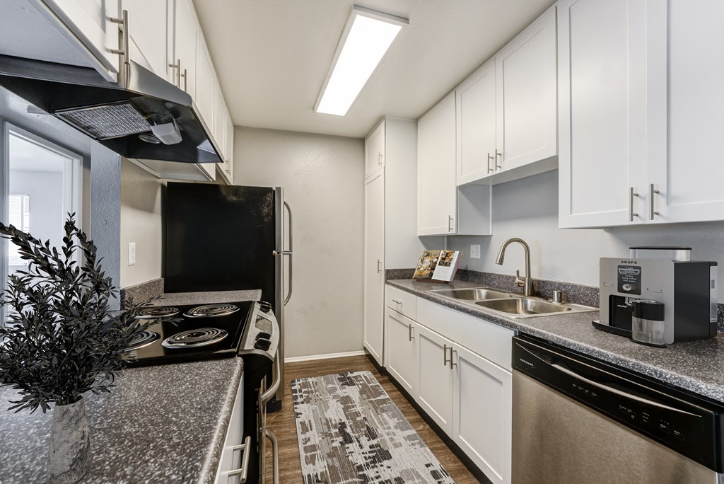 an empty kitchen with granite counter tops and white cabinets