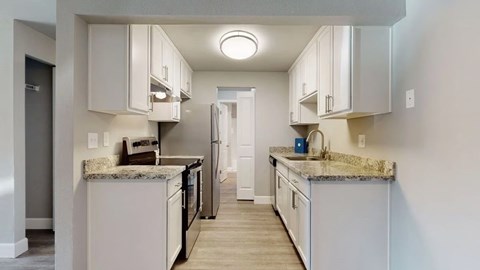 A kitchen with white cabinets and granite countertops.