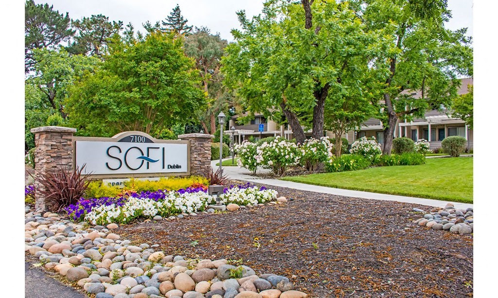 the sign is in front of a yard with rocks and flowers