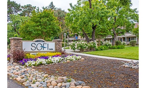 the sign is in front of a yard with rocks and flowers