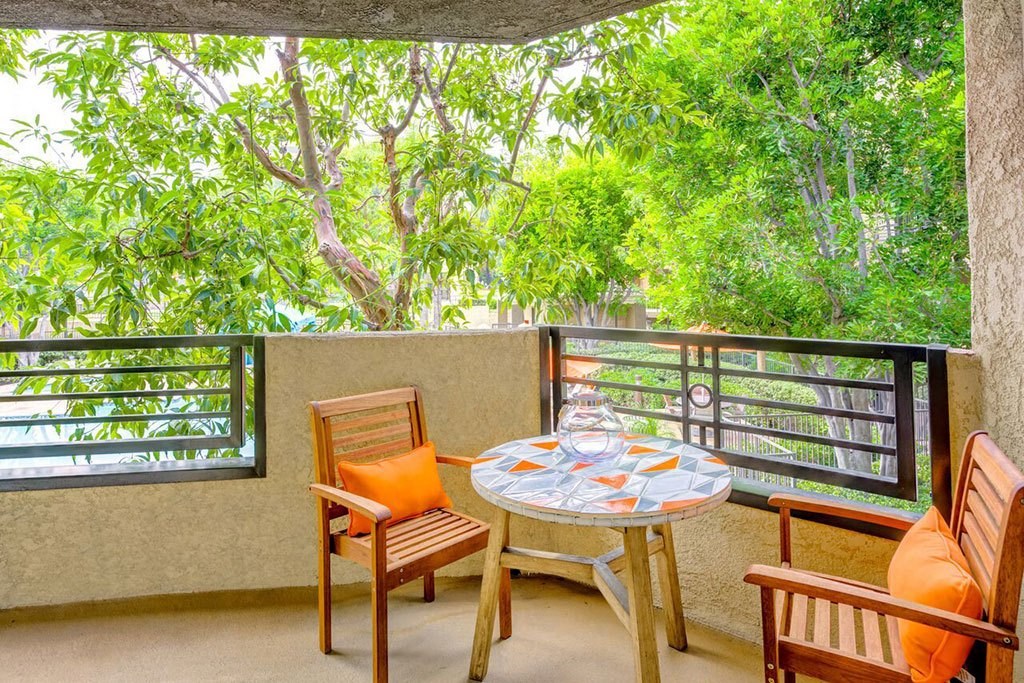a table and chairs on a balcony with trees