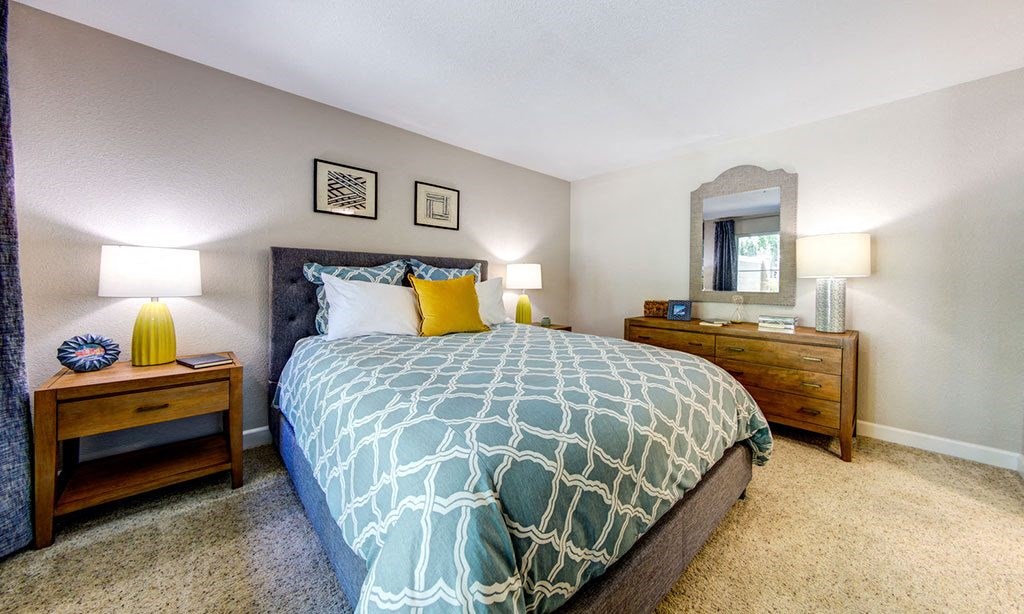 a bedroom with a bed and two night stands and a mirror