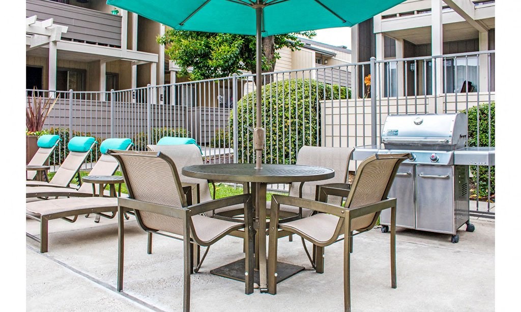 a patio with tables and chairs and a grill