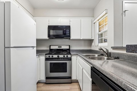A modern kitchen with a black stove and white cabinets.