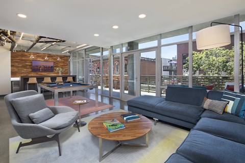 A modern living room with a grey chair, a blue sofa, and a wooden coffee table.