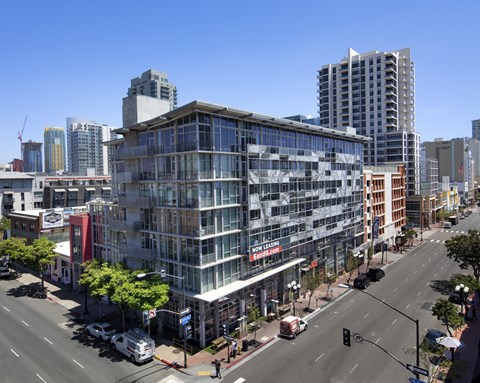 A modern building with glass windows is in the foreground of a city street.