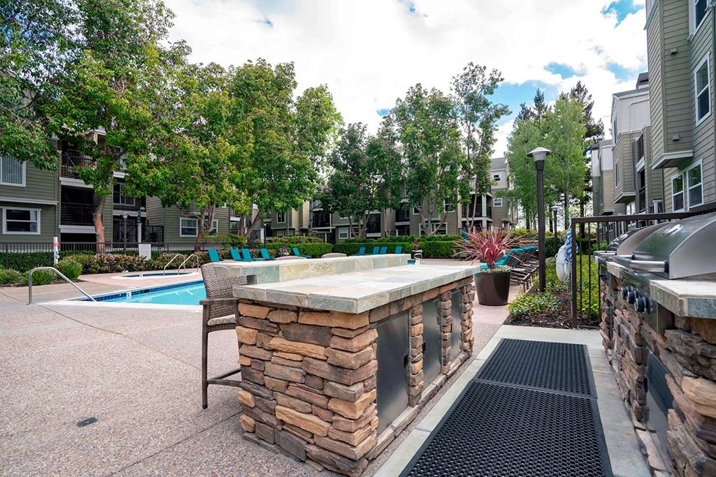 a pool with a hot tub in front of a building with trees
