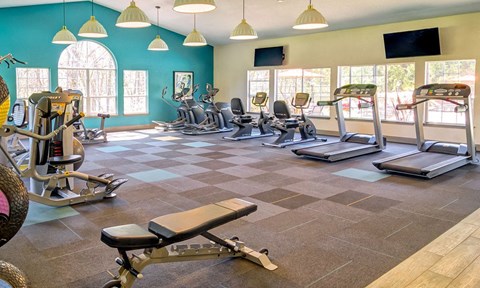 a gym with cardio equipment and windows
