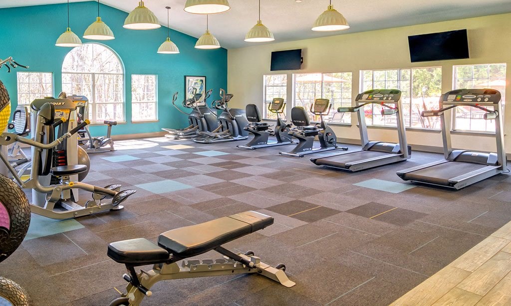 a gym with cardio equipment and windows