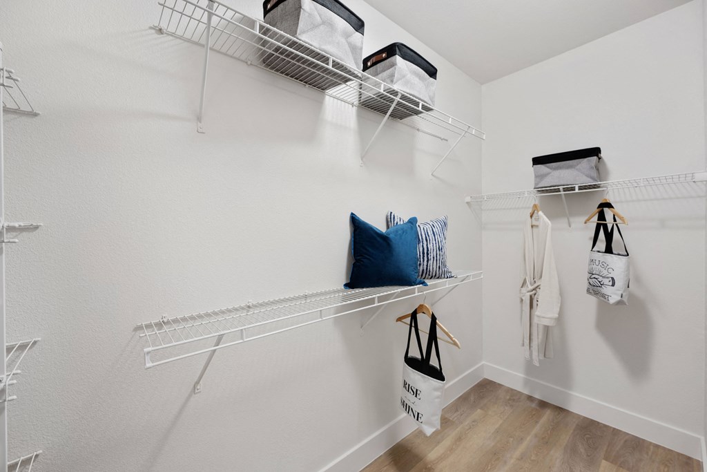 a spacious closet with white walls and shelves and bags hanging on the wall