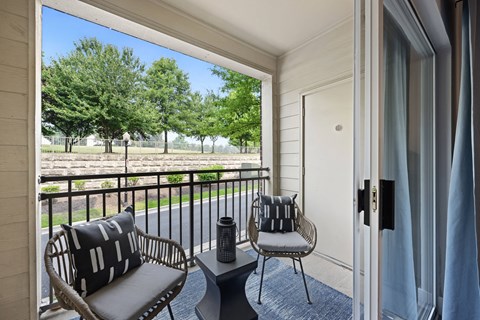 a balcony with two chairs and a table and a door