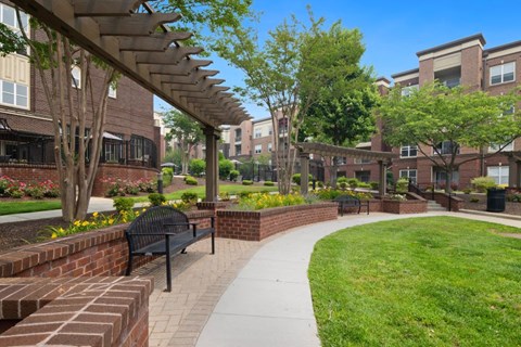 a walkway with benches and grass in front of a building