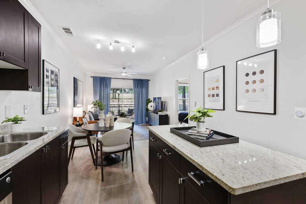 an open kitchen and dining room with a marble counter top and a table and chairs