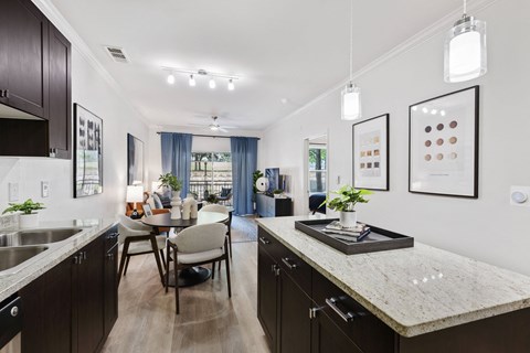 an open kitchen and dining room with a marble counter top and a table and chairs